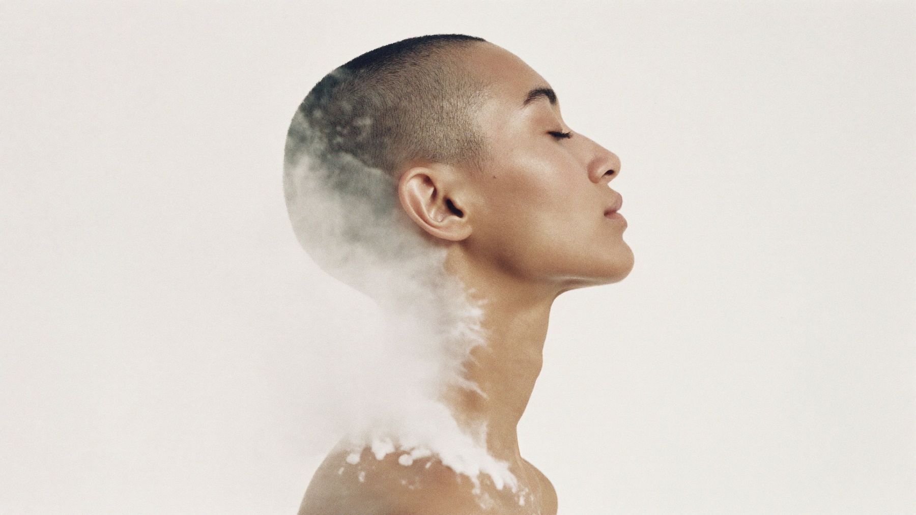A woman in profile with eyes closed, her shoulders dissolving into mist